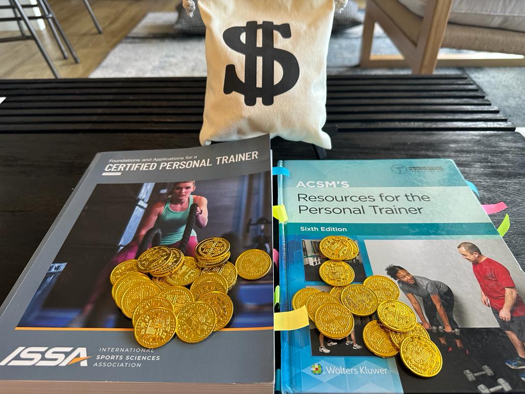 ISSA vs ACSM - Which Fitness Certification is Best? 44 ACSM vs ISSA - ISSA and ACSM textbooks on a table with gold coins and a bag with a money sign - which is more costly