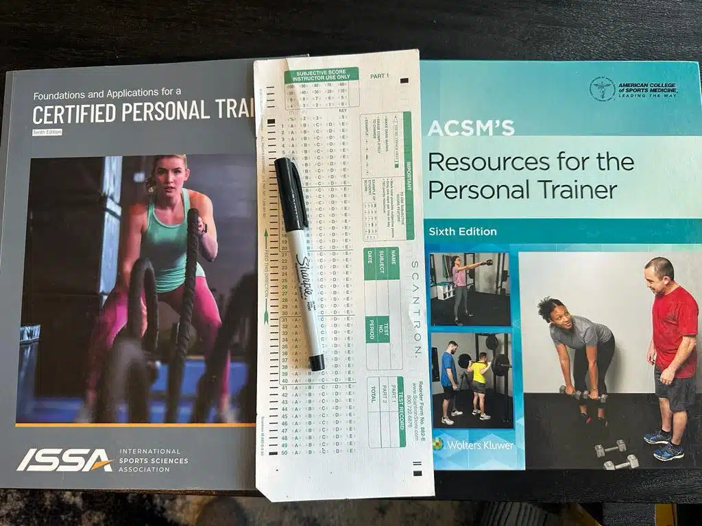 ISSA vs ACSM - Which Fitness Certification is Best? 57 ISSA and ACSM textbooks next to the final exam laid out with a sharpie - which is harder ISSA or ACSM