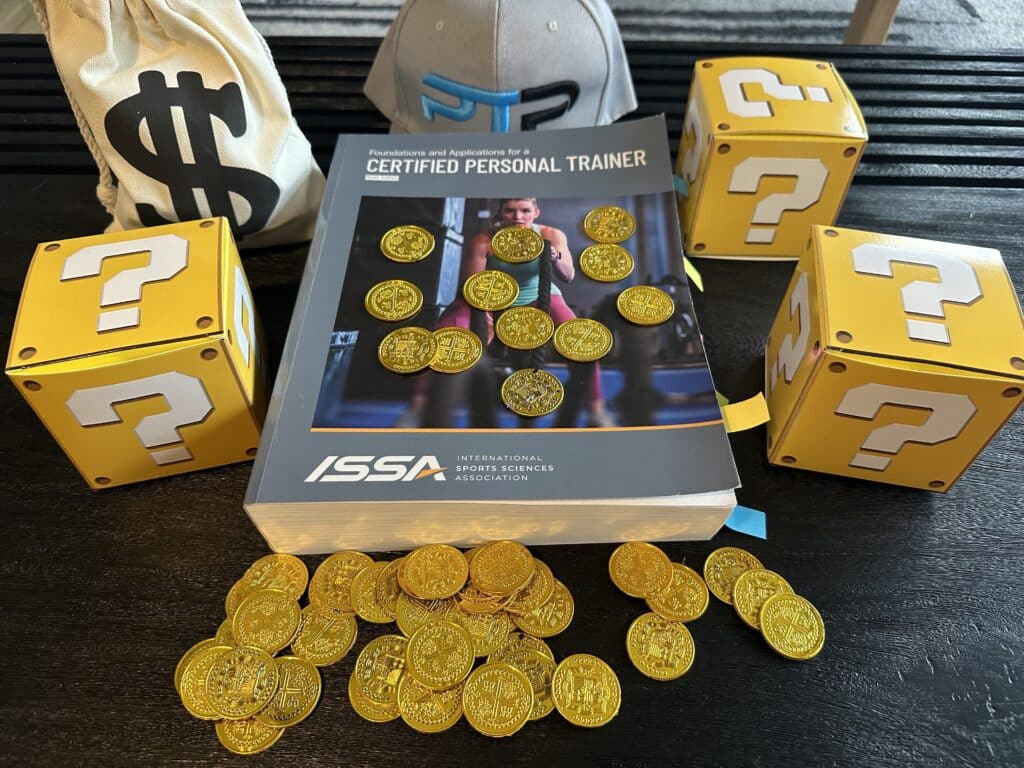 issa cpt costs and course options - ISSA textbook with gold coins on table