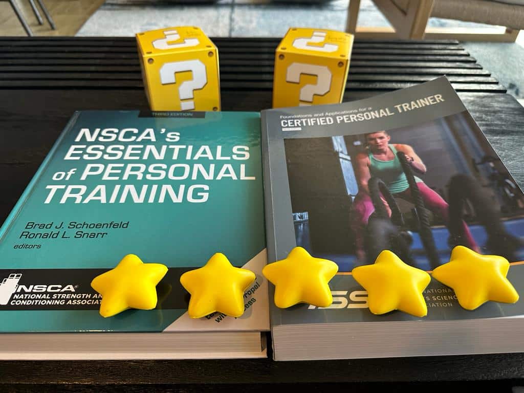 ISSA vs NSCA overal ratings - textbooks for ISSA and NSCA on desk with gold stars on top and yellow question boxes