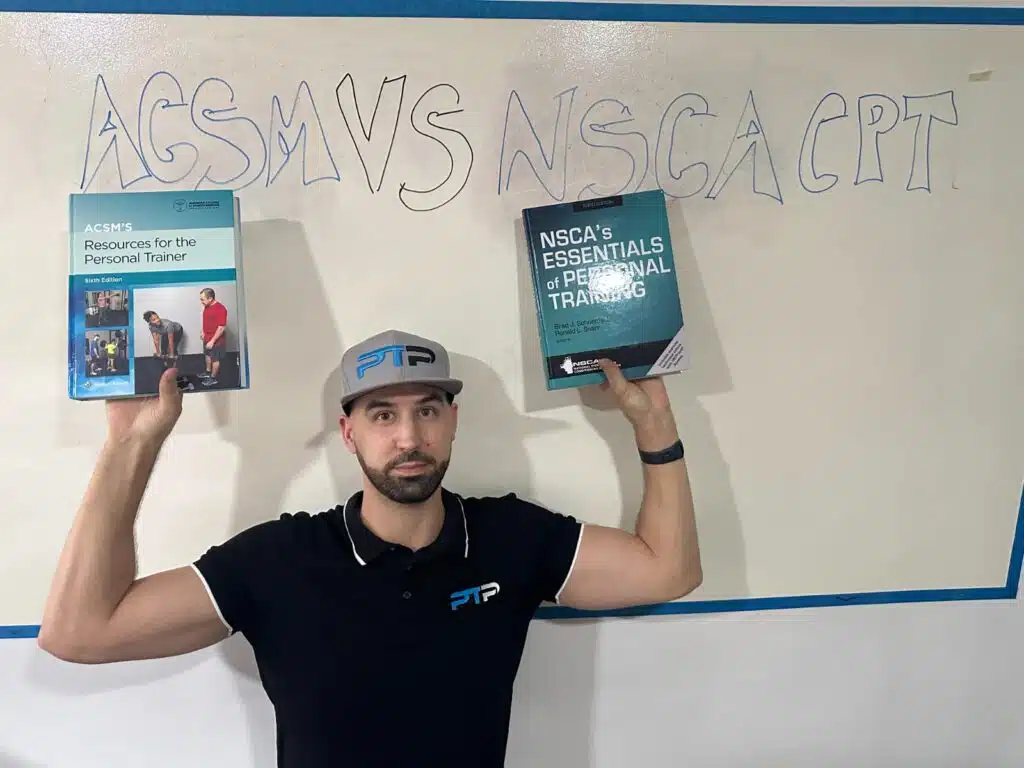 NSCA vs ACSM - Tyler stands in front of white board  with lettering holding up ACSM and NSCA books - pros and cons of acsm vs nsca 