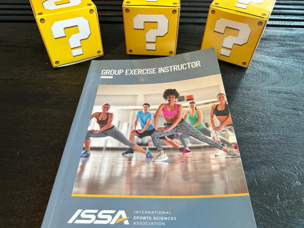 best group exercise certifications - ISSA group exercise instructor textbook on table with yellow question mark boxes