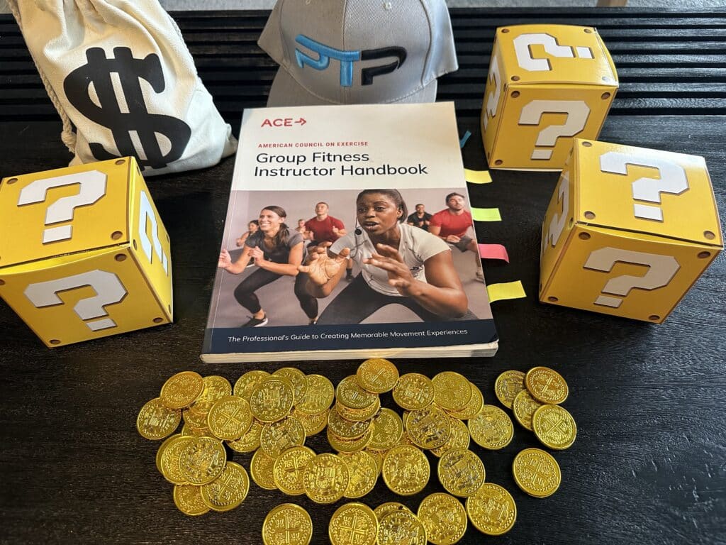 ace group fitness instructor review - ace handbook next to gold coins and yellow question mark boxes and ptpioneer hat - how much is the ace group exercise certification 