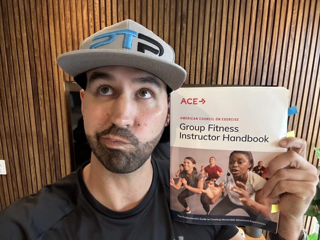 Ace group fitness instructor - Tyler holds up ace textbook - is the ace gfi worth it