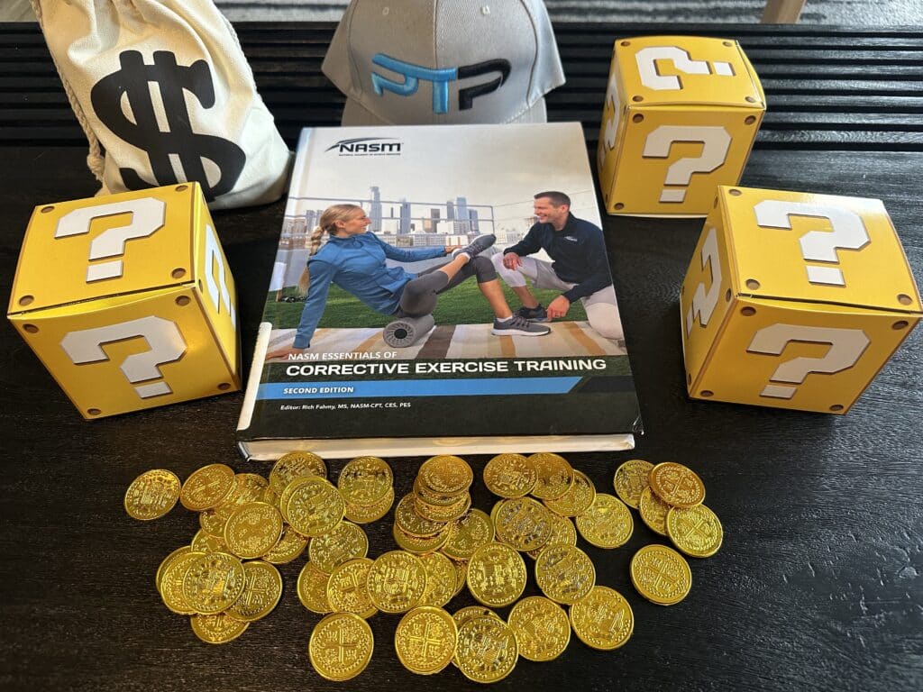 NASM CES cost and course options - NASM CES textbook laid out on table with gold coins and mystery boxes - how much does NASM cost?