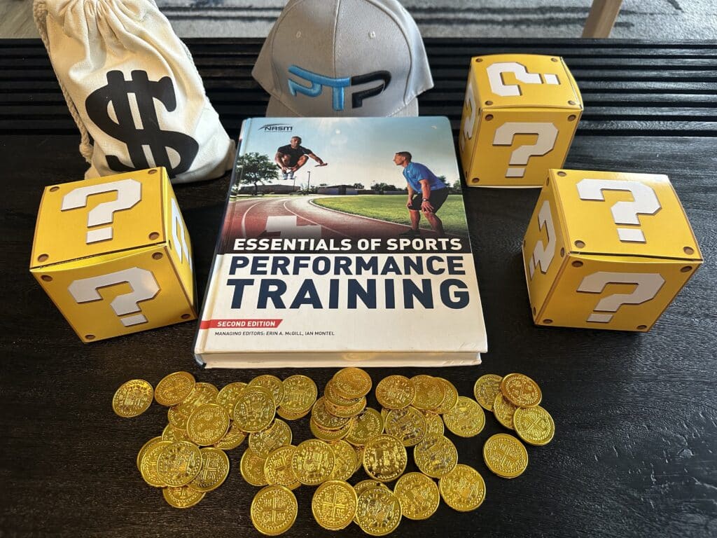 NASM pes cost and course options - NASM textbook laid out on table with gold coins and mystery boxes - how much does NASM PES cost?