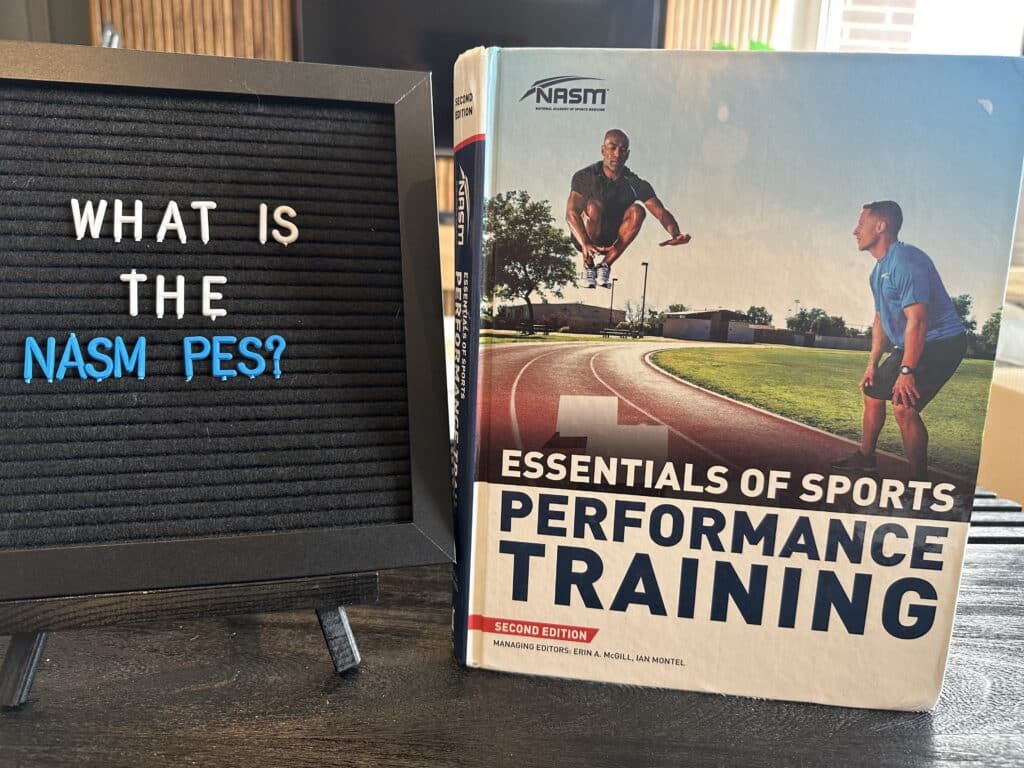 Board with letters spelling out "what is the nasm pes" next to the nasm textbook for performance enhancement