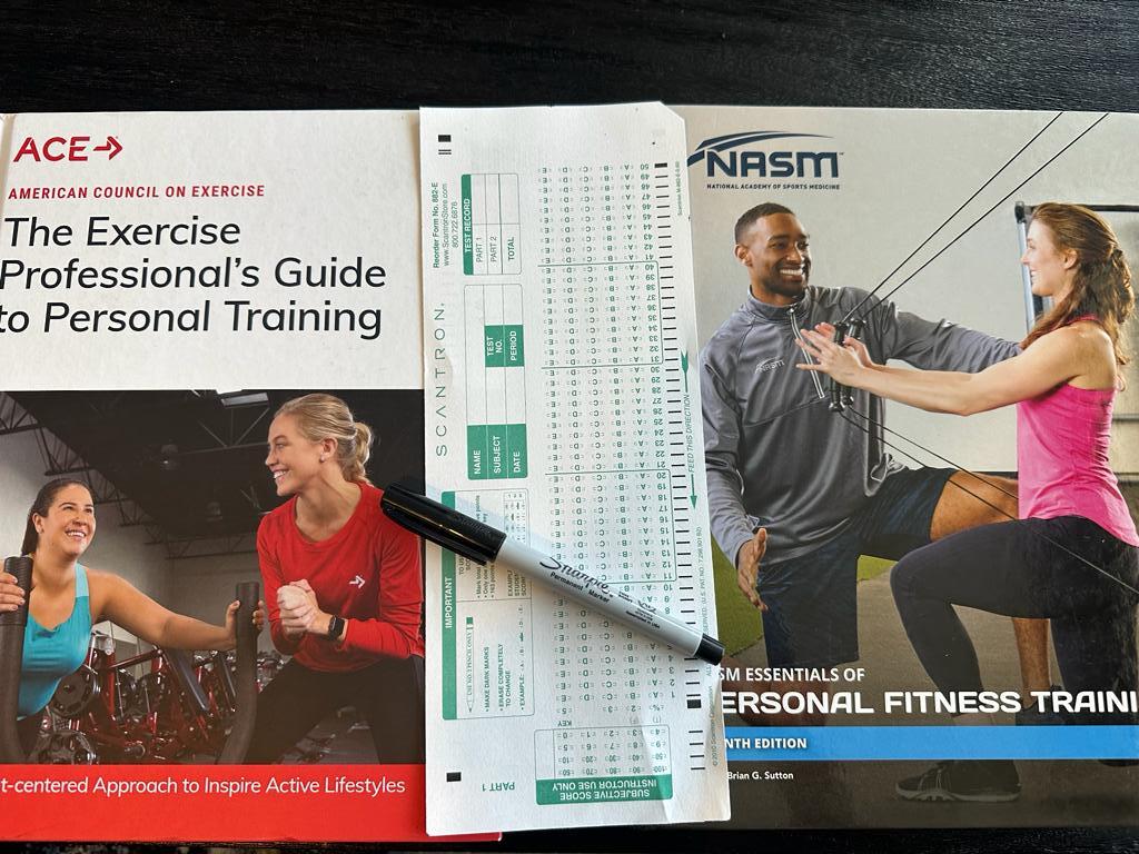 ACE vs NASM final exams - NASM and ACE textbooks with scantron exam sheet next to them and sharpie pen - how hard are the finals