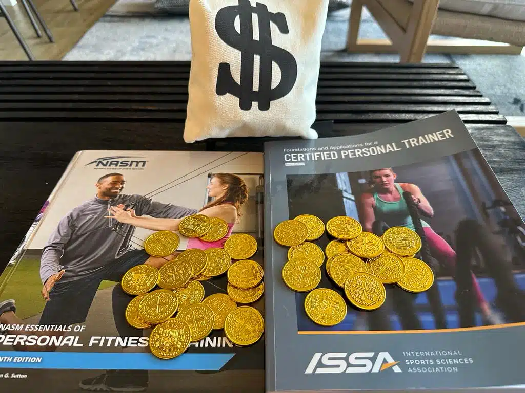 Comparing NASM and ISSA: Which Certification is Right for You? 47 ISSA vs NASM - ISSA and NASM textbooks on desk with gold coins and money bag - which costs more?