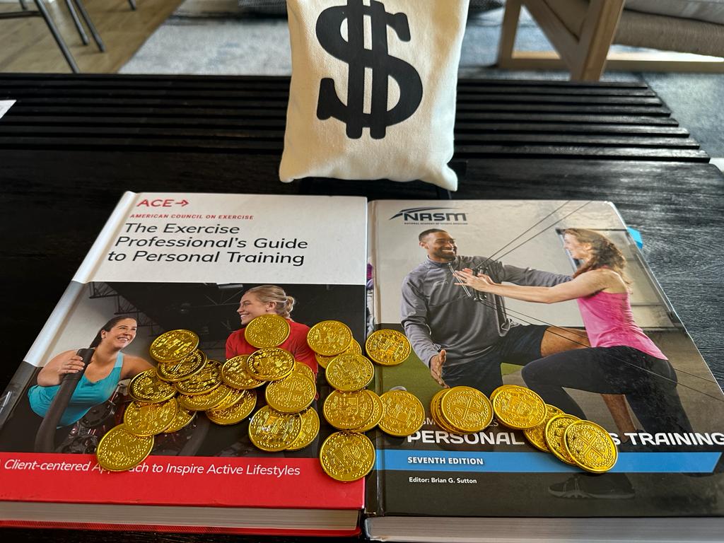 NASM vs ACE pricing - ACE and NASM textbooks on table covered in gold coins next to money bag - which certification costs more