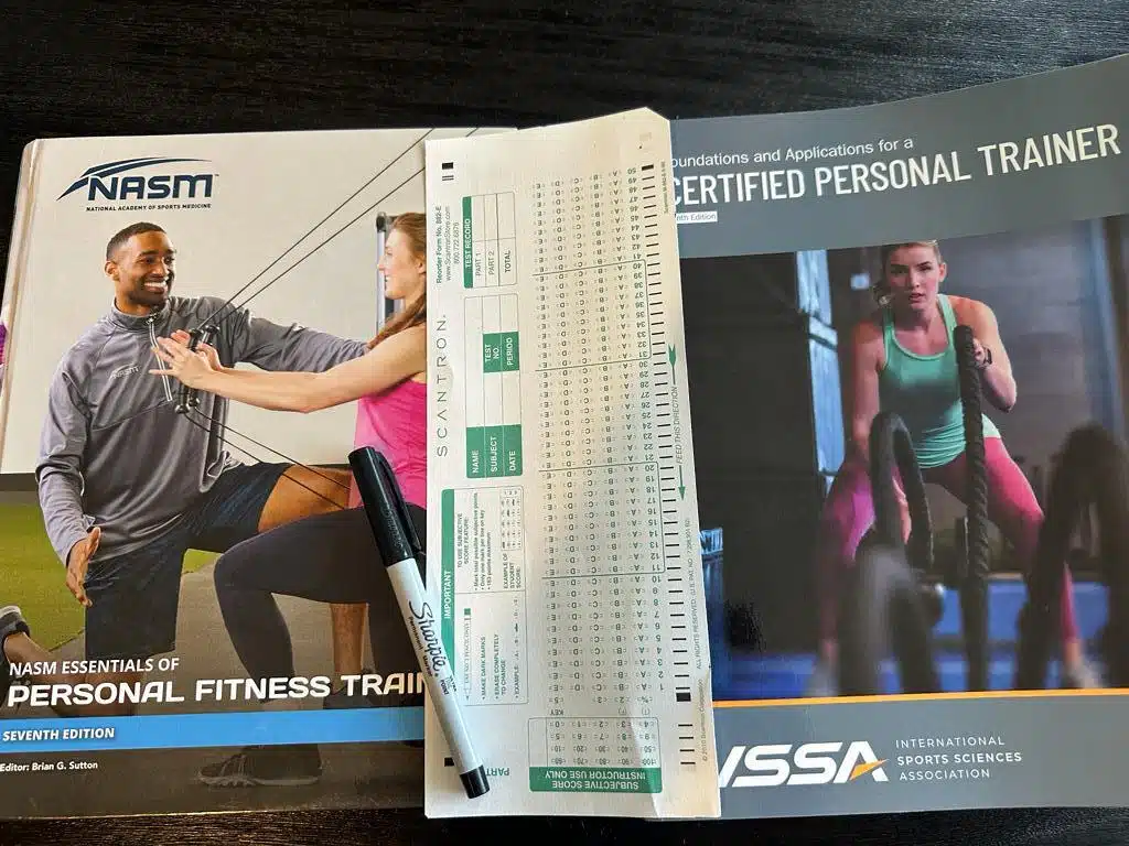 Comparing NASM and ISSA: Which Certification is Right for You? 61 ISSA vs NASM - CPT books next to each other with scantron exam sheet between them and sharpie - which exam is harder