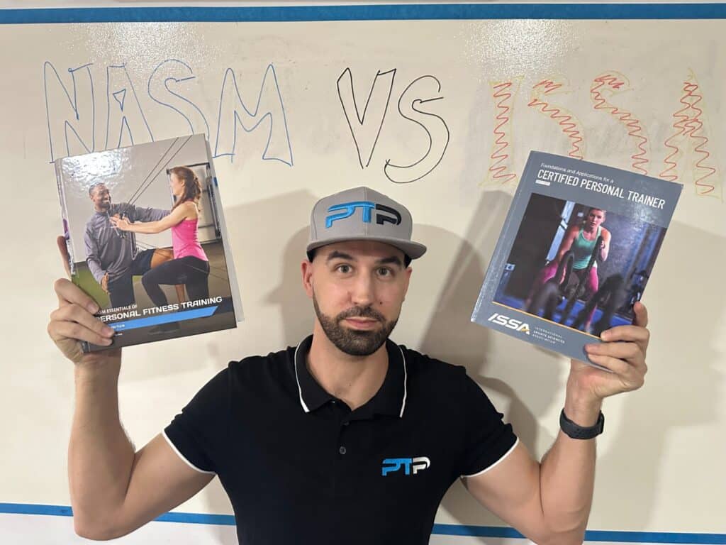 NASM vs ISSA - Tyler Read holds up NASM and ISSA textbooks in front of white board with lettering - pros and cons of ISSA vs nasm