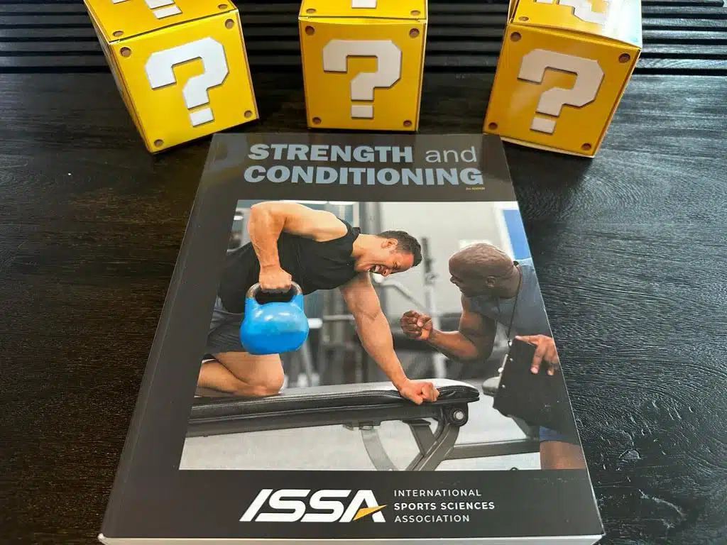 5 Best Strength and Conditioning Certifications (CSCS, PES, SCCC) 14 ISSA strength and Conditioning textbook laid out on table with yellow question boxes - top strength certifications