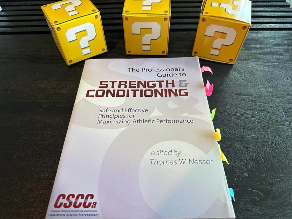 top strength and conditioning certifications - cscca textbook on table with yellow question boxes