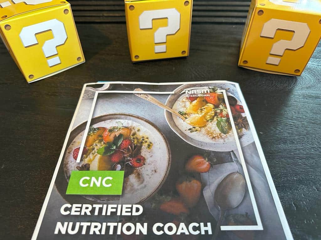 top Nutrition coaching certification - NASM CNC textbook laid out on table with yellow boxes with question marks