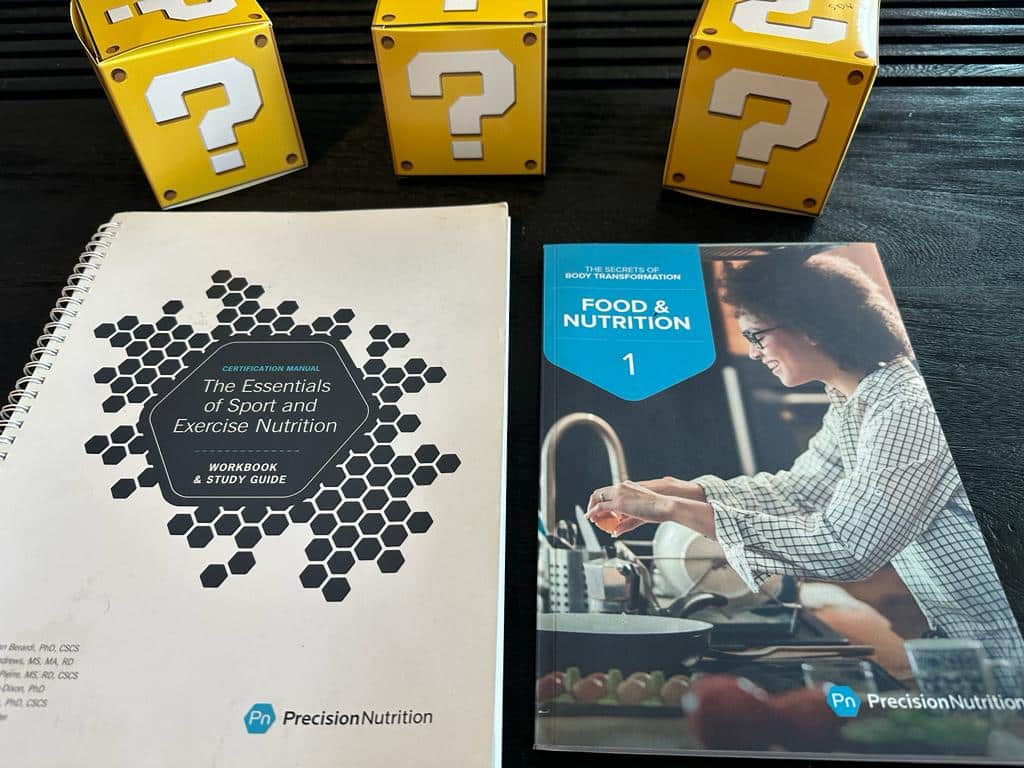 top nutrition certifications - precision nutrition textbook on table with yellow question mark boxes 