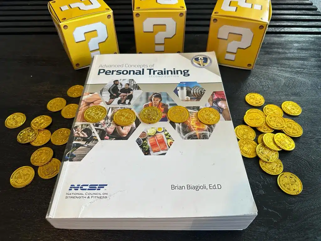The 9 Cheapest Personal Training Certifications 20 cheapest personal training certification - NCSF textbook laid out on table with gold coins and mystery boxes - how much does NCSF CPT cost?