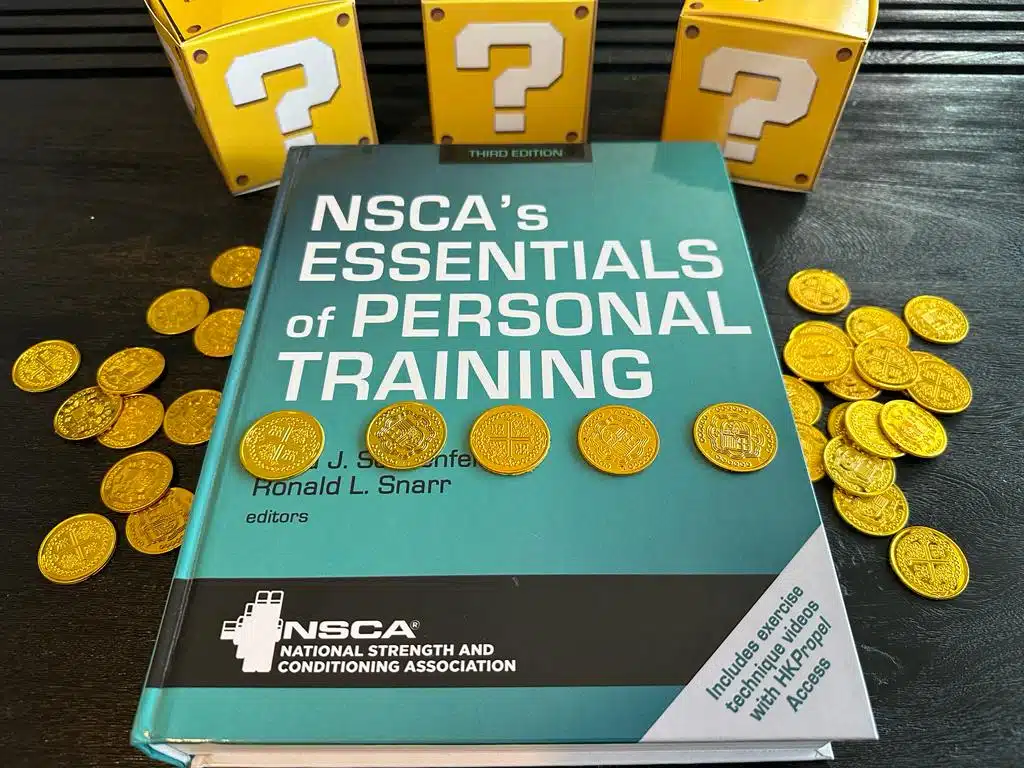 The 9 Cheapest Personal Training Certifications 16 Cheapest personal training certifications - NSCA textbook laid out on table with gold coins and mystery boxes - how much does NSCA CPT cost?