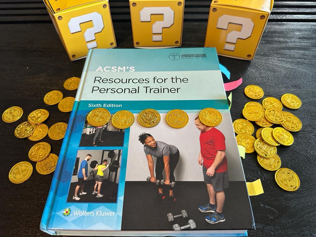 Cheapest personal training certification - ACSM textbook laid out on table with gold coins and mystery boxes - how much does ACSM CPT cost?