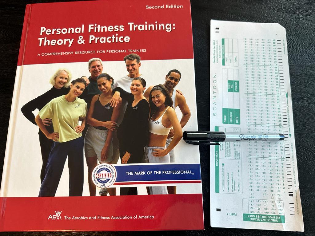 Personal training certifications - AFAA CPT textbook laid out with a copy of scantron exam next to it and a sharpie 