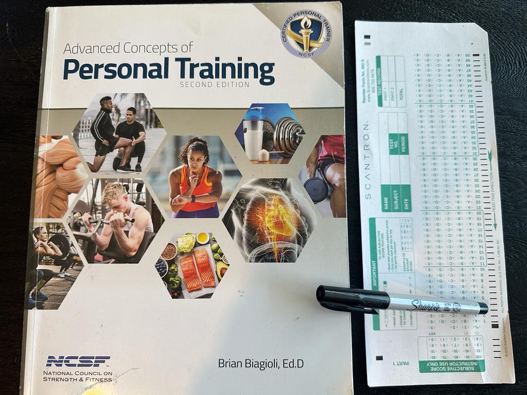 Easy personal training certification - NCSF CPT textbook laid out with a copy of scantron exam next to it and a sharpie 