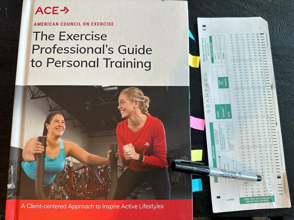 Easiest personal trainer certification - ACE CPT textbook laid out with a copy of scantron exam next to it and a sharpie 