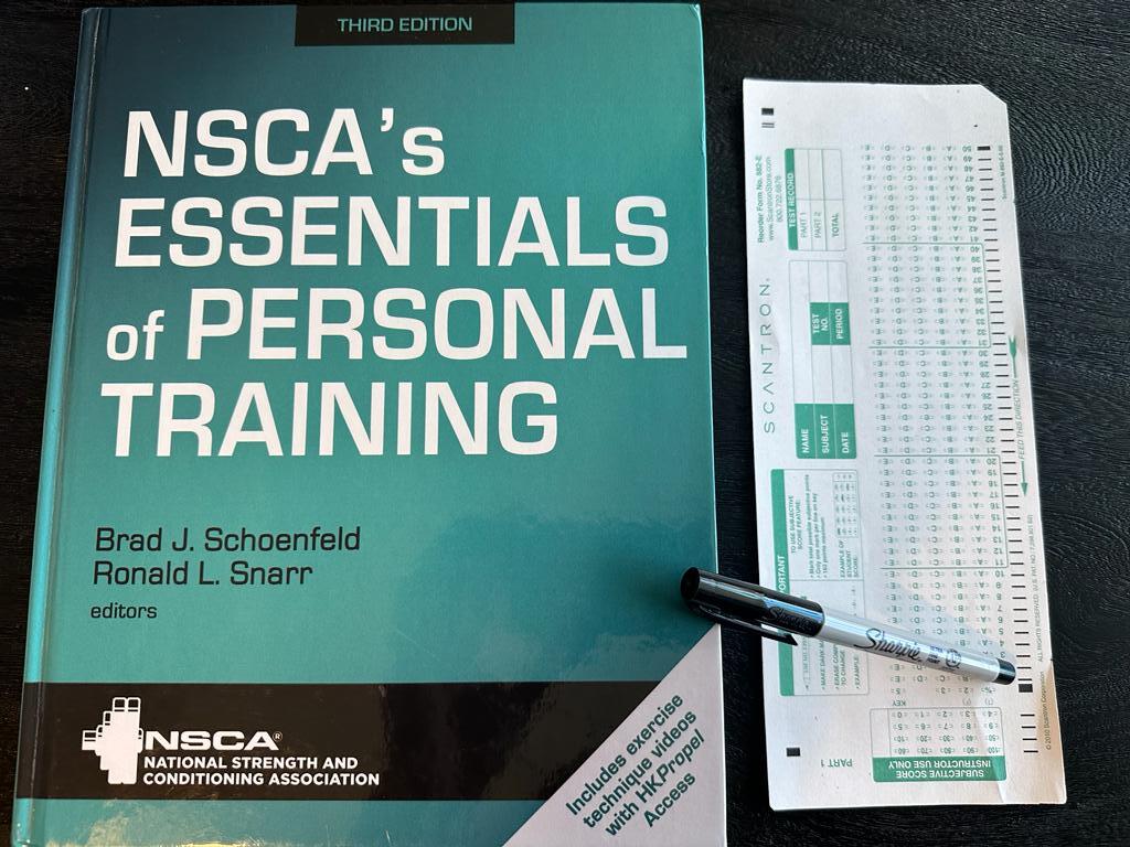 Easy personal training certification - NSCA CPT textbook laid out with a copy of scantron exam next to it and a sharpie 