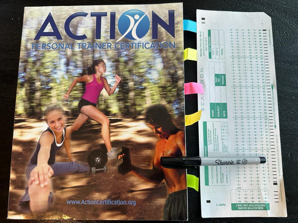 Easiest personal trainer certifications - Action CPT textbook laid out with a copy of scantron exam next to it and a sharpie 