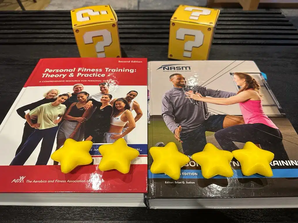 NASM vs AFAA Certification Comparison Review 28 NASM vs AFAA - textbooks on table with yellow stars and question mark boxes - which cpt is best overall?