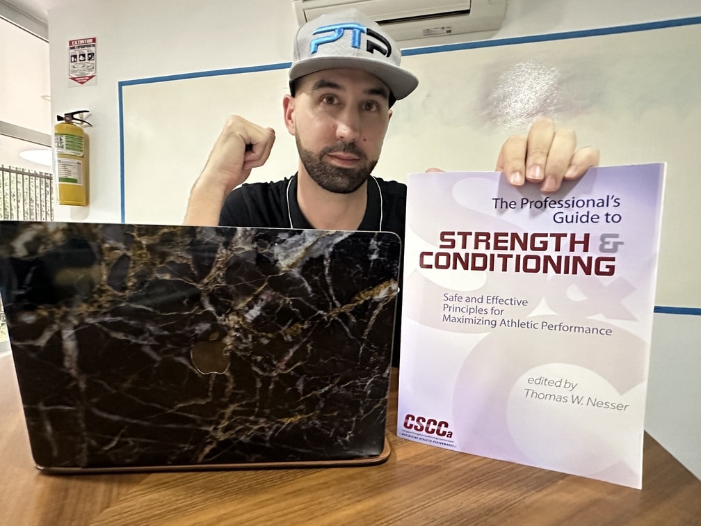 CSCCa review - Tyler Read holds up CSCCa textbook on table next to laptop