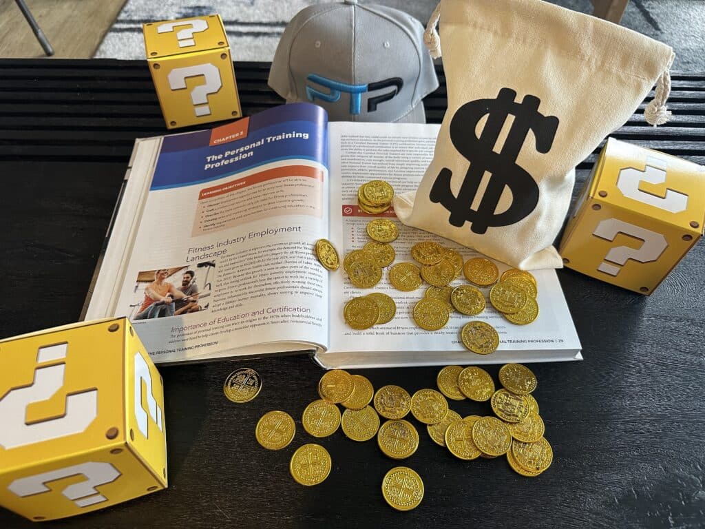 NASM Certification Cost and Packages - NASM textbook with gold coins displayed on table