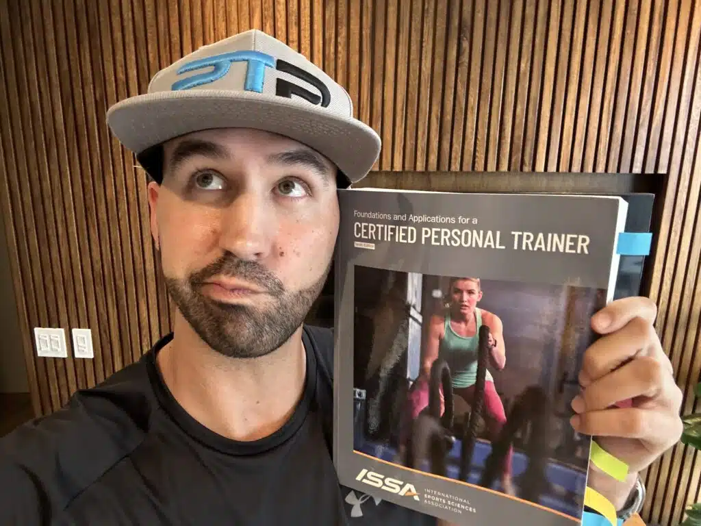 ISSA Training Certification Review 2023 - Is ISSA Worth It? 7 is the issa cpt certification worth it - ISSA training certification - Tyler Read holding textbook deciding if ISSA is worth it