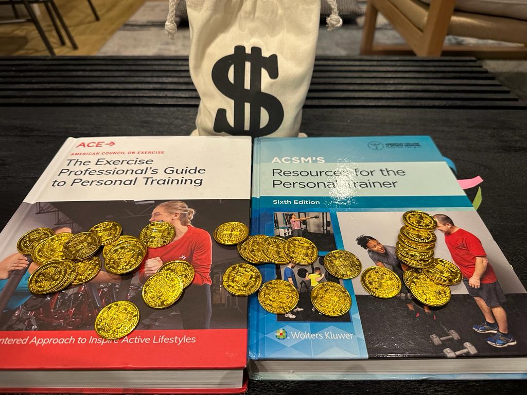 Average income of ACSM and ACE certification. ACSM and ACE personal trainer certification textbooks on table with coins.