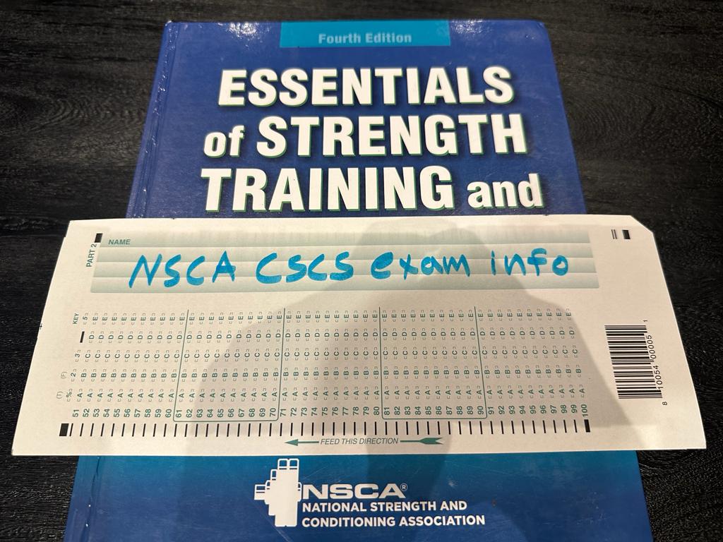 CSCS Exam Info - Pass rate, costs, and more. CSCS textbook and exam worksheet laid out on table in preparation for CSCS exam.