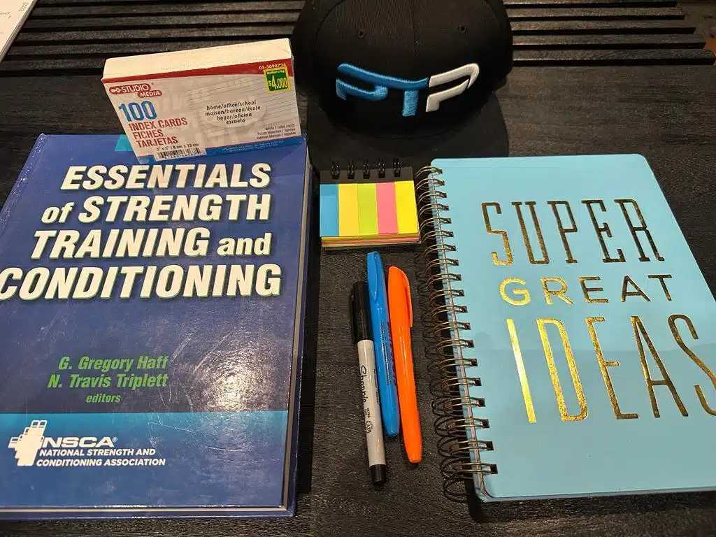 The Complete CSCS Exam Prep - How to Pass the CSCS Exam 1 Free CSCS exam prep. CSCS textbook laid out with a notebook to prep for the CSCS exam.