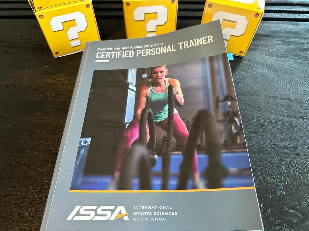 ISSA CPT - best personal trainer certification - ISSA CPT textbook laid out with yellow question mark boxes