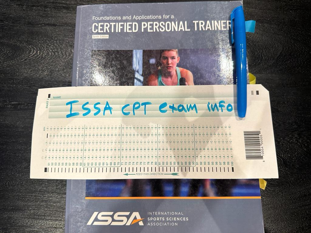 ISSA CPT exam info - ISSA personal trainer textbook placed on table with exam information