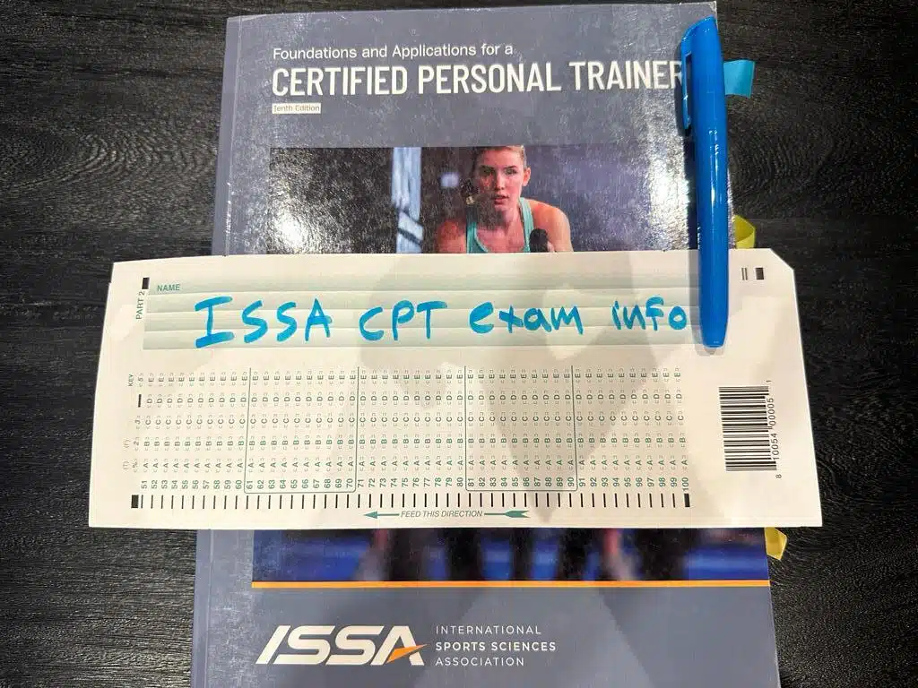 ISSA CPT Exam FAQ - ISSA Pass Rate, Difficulty, Cost 1 ISSA CPT exam info - ISSA personal trainer textbook placed on table with exam information