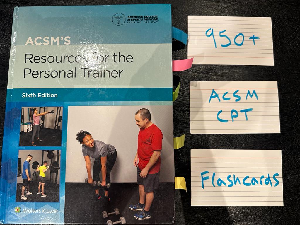 acsm flashcards - ACSM textbook laid on table with acsm flashcards to study for the acsm cpt