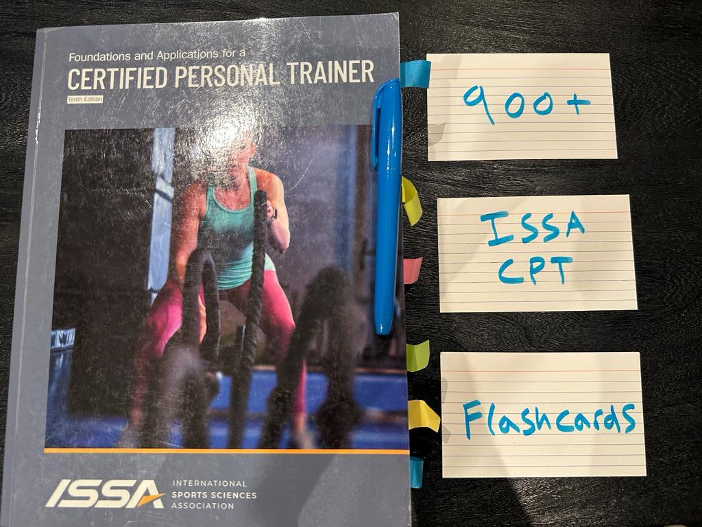 ISSA textbook laid on table with flashcards to study the ISSA personal trainer curriculum