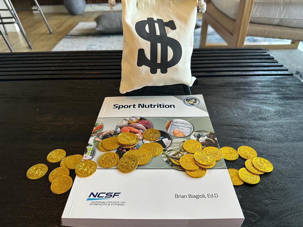 NCSF SNS cost and course packages - NCSF Sports Nutrition Textbook with gold coins on table