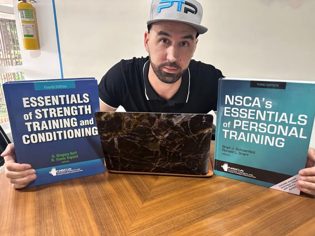 NSCA CPT vs CSCS - Tyler Read holds up CPT and CSCS textbooks on table 