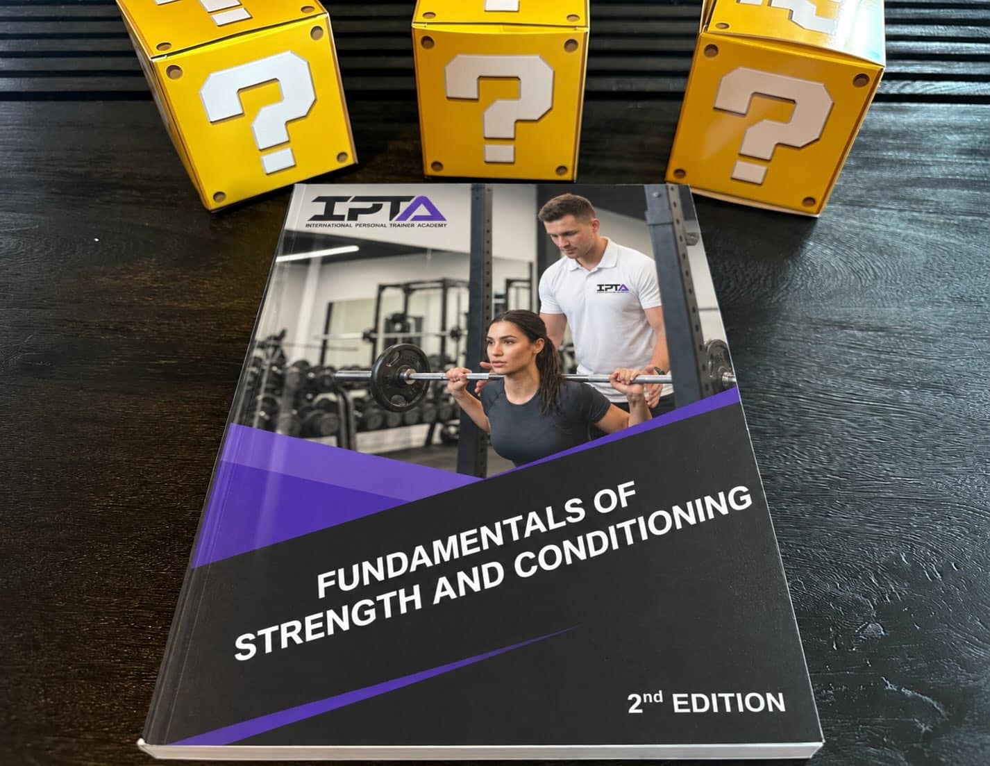 IPTA strength and Conditioning textbook laid out on table with yellow question boxes - top strength certifications