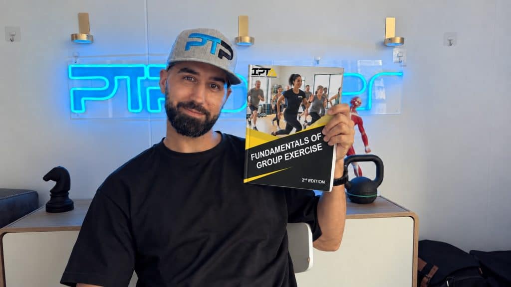 IPTA Group Exercise Specialist Review – Is It Worth It? 3 Tyler holds the Group Exercise Specialist textbook for IPTA.