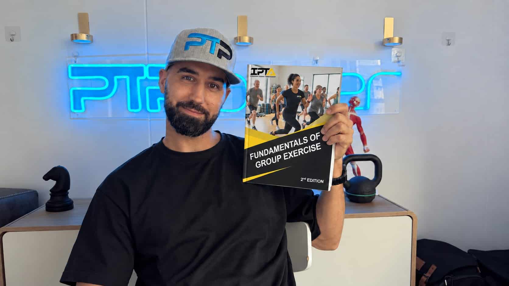 Tyler holds the Group Exercise Specialist textbook for IPTA.